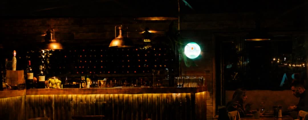 Barra de La Vara de noche, con botellas y lámparas de cobre encendidas