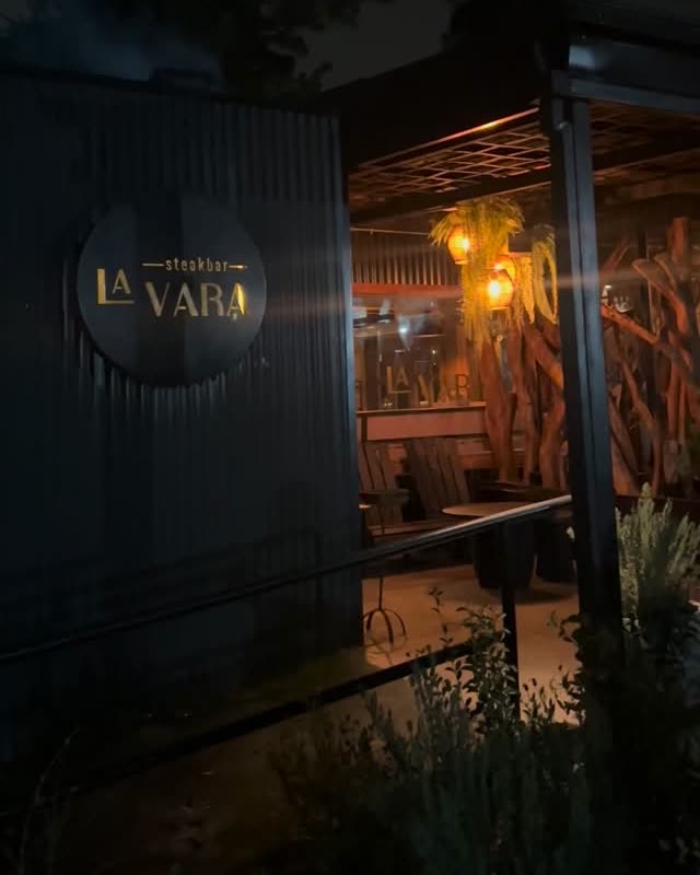 Entrada de La Vara de noche, con el letrero y la terraza al fondo